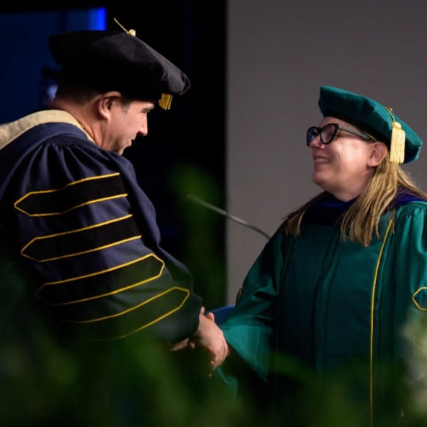 woman in cap and gown shaking hands with man in cap and gown