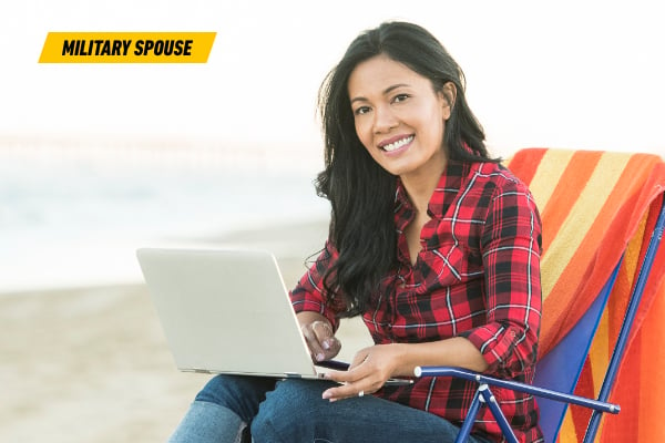 Photo of Chanda sitting on the beach with her laptop
