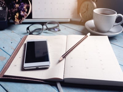 phone on planner with a cup of coffee and glasses
