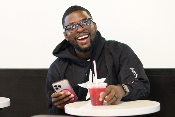Thyshown sitting at a table smiling