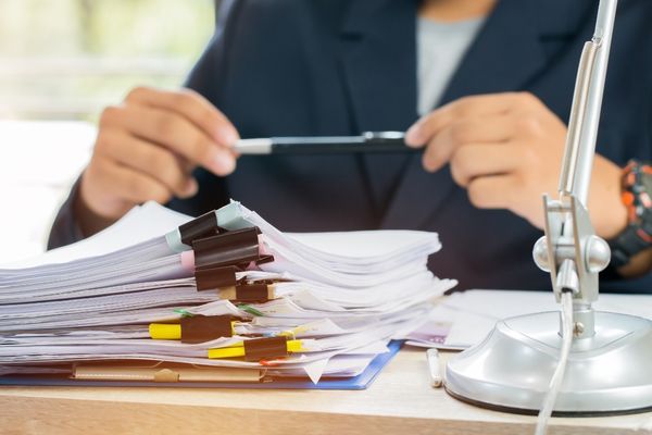 legal studies professional at desk with stacks of contracts