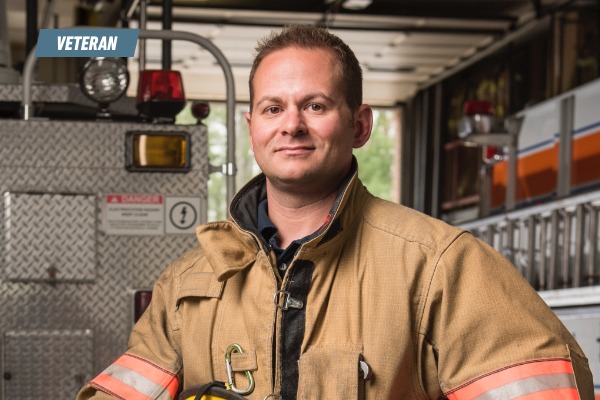 Photo of Earl, in uniform, next to a fire engine